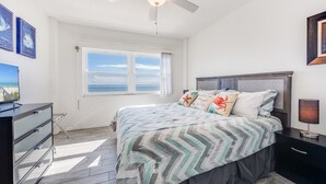 A bedroom with a bed, a desk, a chair, a ceiling fan, and a window with a view. - Salt Life Oasis - Direct Oceanfront, End Unit in Satellite Beach, FL (Satellite Beach)