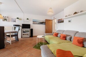 A living room with a sofa, a television, a dining table, and a kitchen area. - Apartment 'Haus Deichblick 2' with Balcony and Wi-Fi (Wangerland)