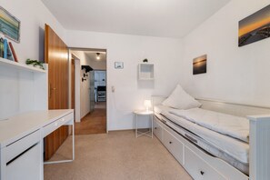 A bedroom with a bed, a desk, a chair, a lamp, and a wardrobe. - Apartment 'Haus Deichblick 2' with Balcony and Wi-Fi (Wangerland)