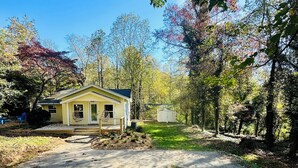 A yellow house with a front porch, surrounded by trees and a clear sky. - Candler Cottage: Close 2 Everything "Asheville" (Candler)