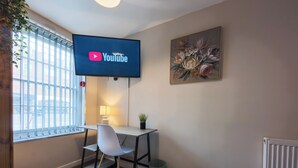 A hotel room with a desk, chair, TV, and a painting on the wall. - Casa Botique - Close To Gunwharf (Portsmouth)