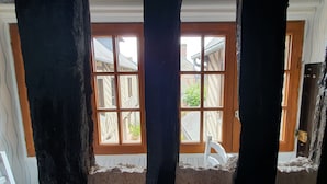 Ein Zimmer mit großem Fenster, Holzbalken und einem weißen Stuhl.