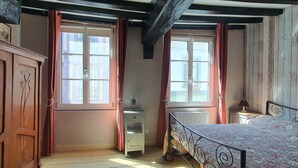 Ein Schlafzimmer mit einem Bett, einem Nachttisch, einem Heizkörper und einem Fenster mit Vorhängen.