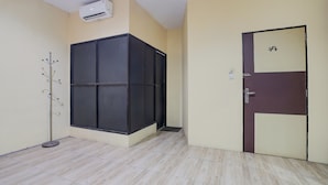 Une pièce avec un sol carrelé, une porte noire et beige, et un appareil de climatisation fixé au mur.