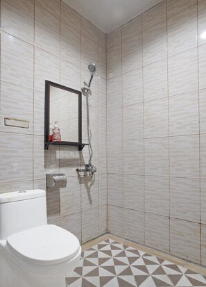 A small bathroom with a toilet, a shower, and a mirror.