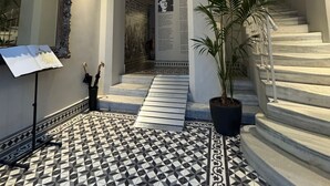 Un amplio pasillo con piso de baldosas, una escalera y un espejo grande.