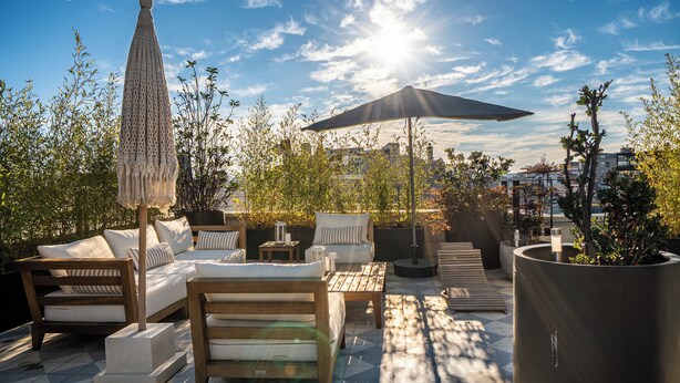 Terraza en la azotea con mobiliario exterior, una sombrilla grande y una planta en maceta.