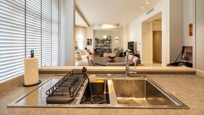 Una cocina moderna con un lavamanos de acero inoxidable, un escurreplatos y un perchero para toallas.