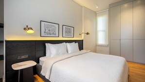 Un dormitorio moderno con cama, mesita de noche y lámpara de pared.