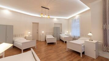 A modern hotel room with four single beds, a desk, and a small table.