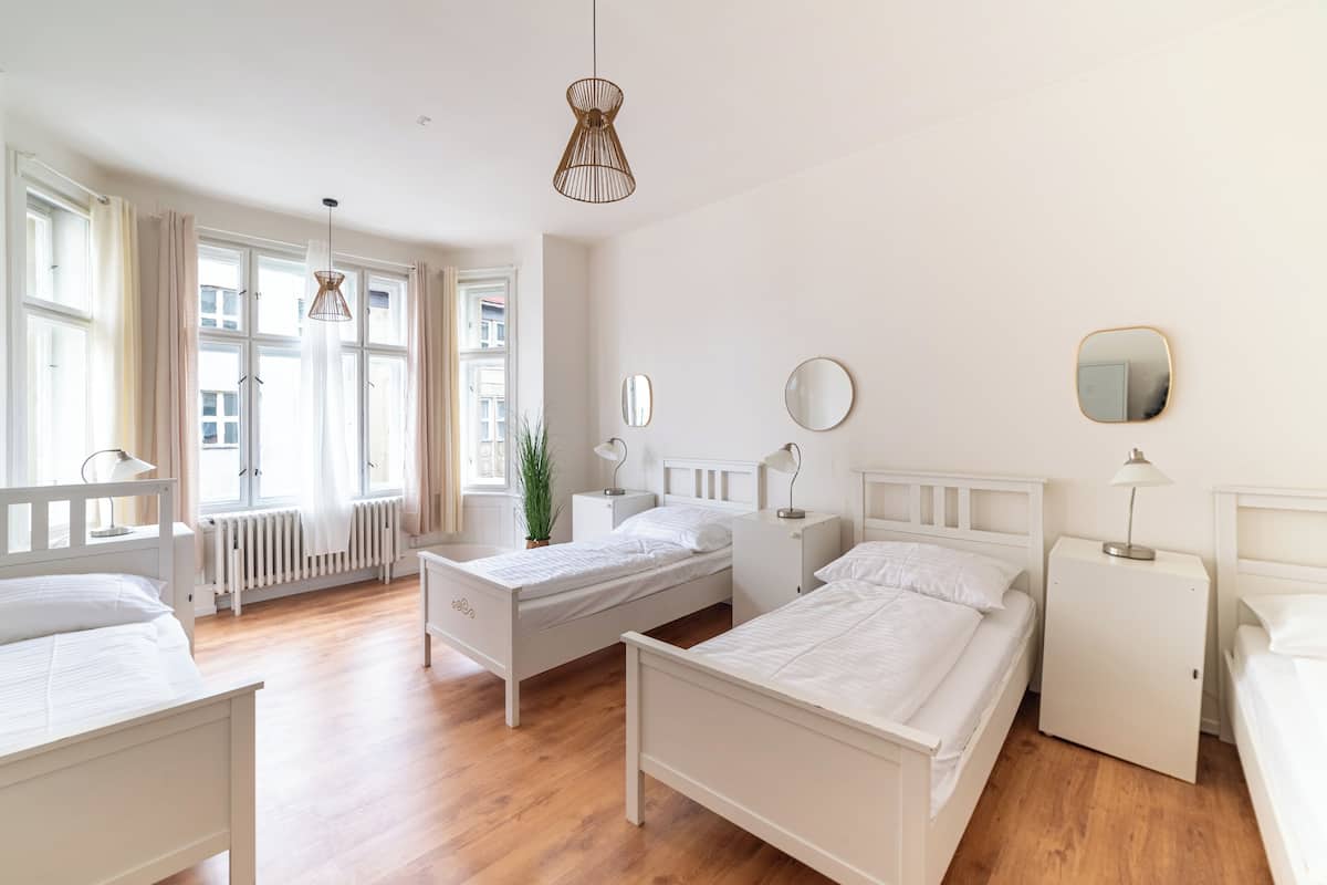A room with three beds, a small white cabinet, and a potted plant.