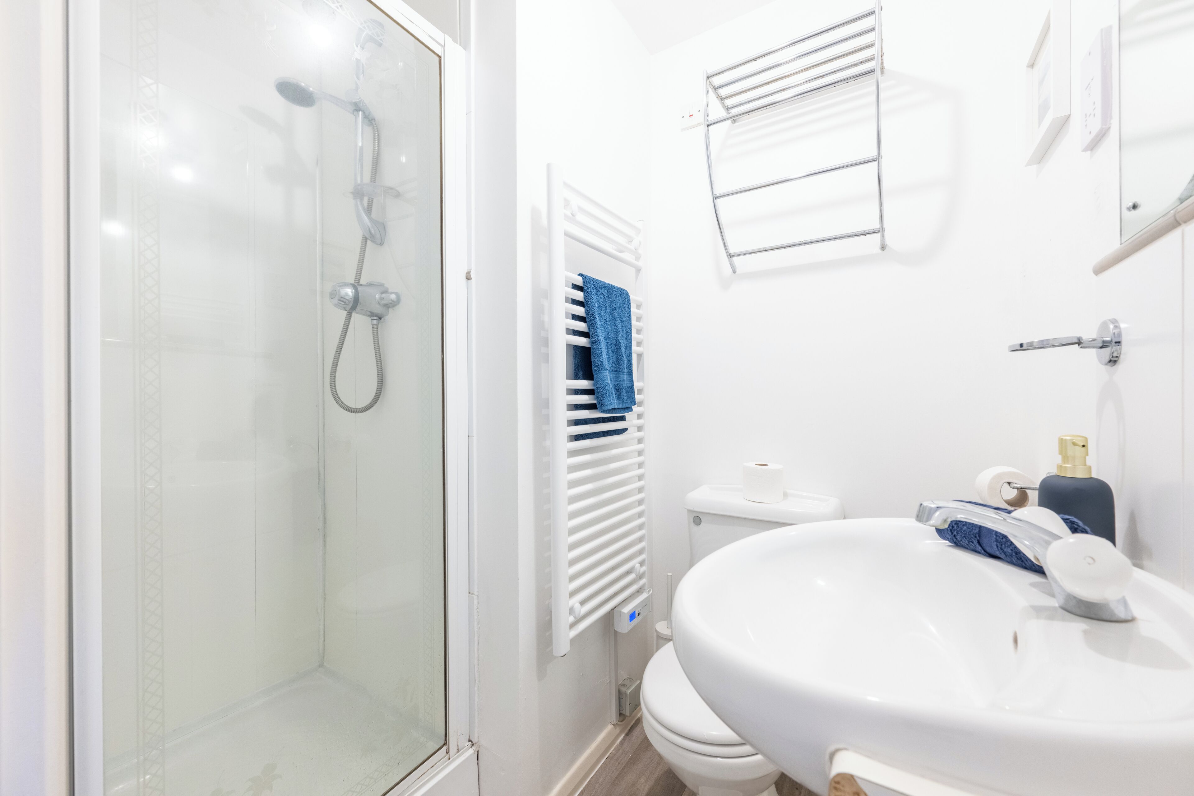 Un baño moderno con ducha de vidrio, lavamanos blanco y retrete.