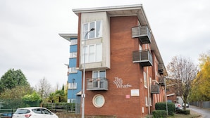 A multi-story residential building with a brick facade, balconies, and a sign reading "The Sand Wharf." - Modern 2BR Apartment with Water Views (Cardiff)