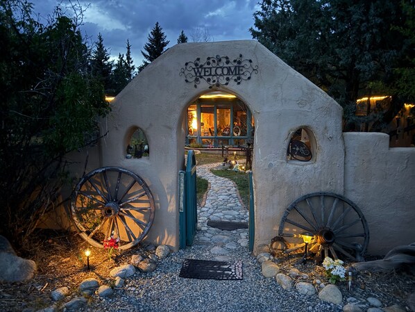 Un arco de bienvenida rústico con un camino de piedra que lleva a un edificio.