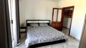 Un dormitorio con cama, un armario de madera y una puerta que da a otra habitación.