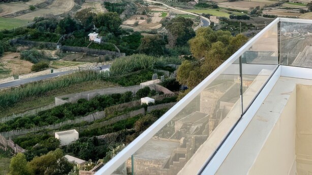 Vista panorámica de un paisaje costero con una colina destacada, una carretera y edificios a lo lejos.