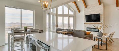A spacious kitchen with a large island, wooden beams, and a stone fireplace.