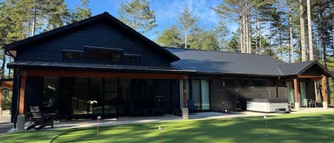 Une maison moderne dotée d’une grande terrasse, d’un patio couvert et d’une pelouse bien entretenue.