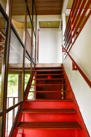 Una escalera con escalones rojos y barandillas de metal que conduce a un piso superior.