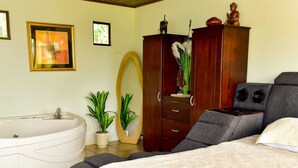 Une chambre avec un grand lit, une armoire en bois, une baignoire et une planche de surf.