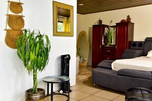 Une pièce comprenant un lit, un bureau, une plante en pot et un miroir.