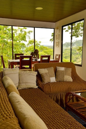 Une pièce comprenant un lit, une table et des chaises, avec vue sur la verdure environnante.