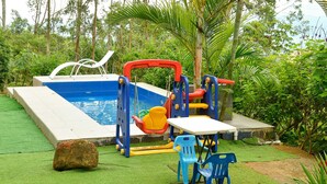 An outdoor swimming pool with a slide and a small table with chairs.