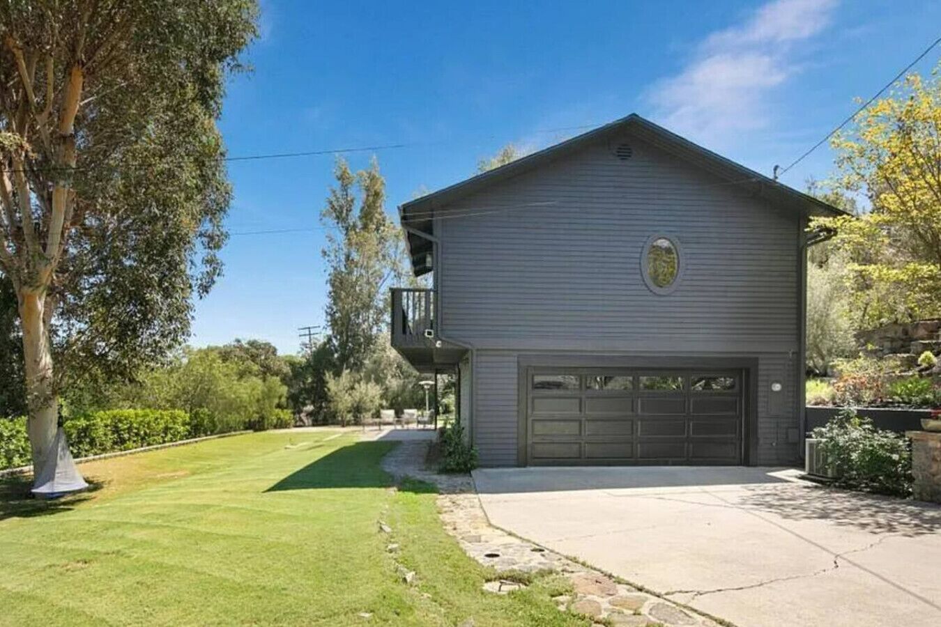 A two-story house with a garage, surrounded by a well-maintained lawn and trees.