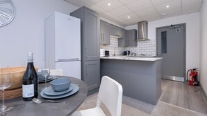 Una cocina moderna con armarios grises, un refrigerador blanco y una pequeña isla con microondas.