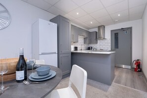 Een moderne keuken met grijze kastjes, een witte koelkast en een klein kookeiland met een magnetron.