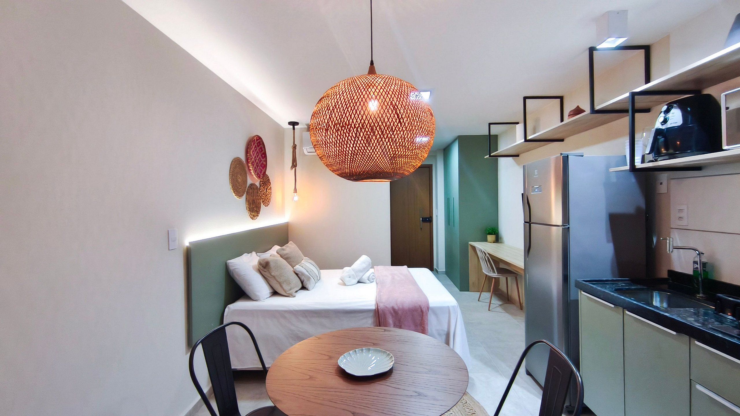 A compact hotel room with a bed, bedside table, and a small dining area.