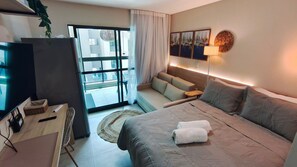 Una habitación de hotel moderna con cama, televisor, escritorio y vistas al exterior.