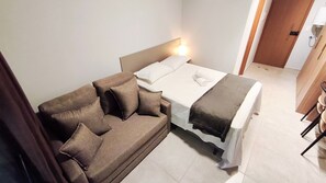 Ein Hotelzimmer mit einem Bett, einem Sofa, einem Nachttisch und einer Tür.