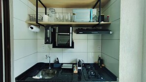 A compact kitchen with a microwave, oven, and gas stove. - Max Carneiros Suites by CTA (Tamandaré)