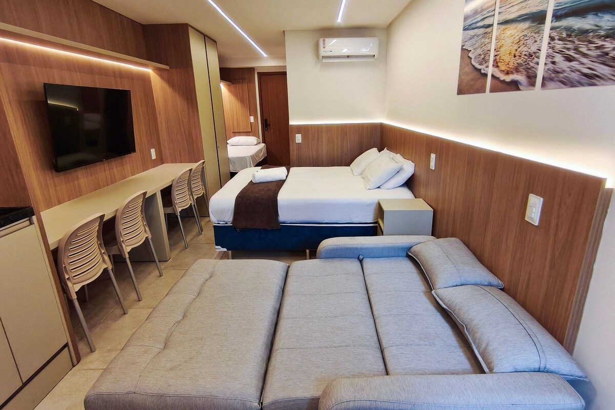 Une chambre d’hôtel de taille réduite, comprenant un lit, une télévision, un bureau et des chaises.