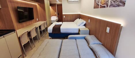 A compact hotel room with a bed, a TV, a desk, and chairs.