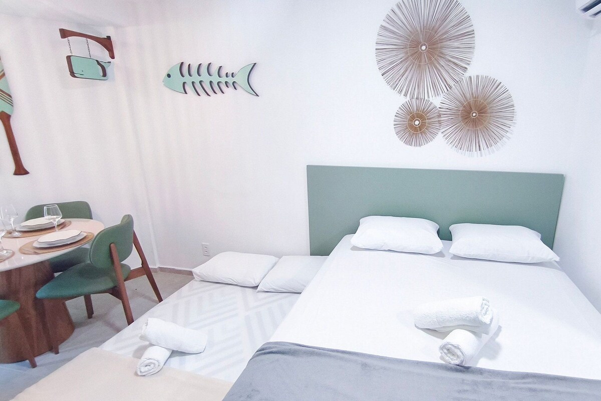 Une chambre à coucher comprenant un lit, des oreillers, une tête de lit, un bureau avec une chaise et des éléments de décoration murale.