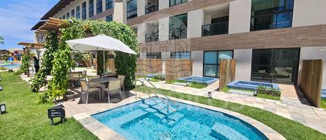 A modern building with a swimming pool, outdoor seating, and a view of a pool area.
