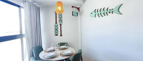 Un comedor con una mesa redonda, sillas y una lámpara colgante.