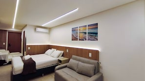 Une chambre d’hôtel équipée d’un lit, d’un canapé, d’une petite table et d’un climatiseur fixé au mur.
