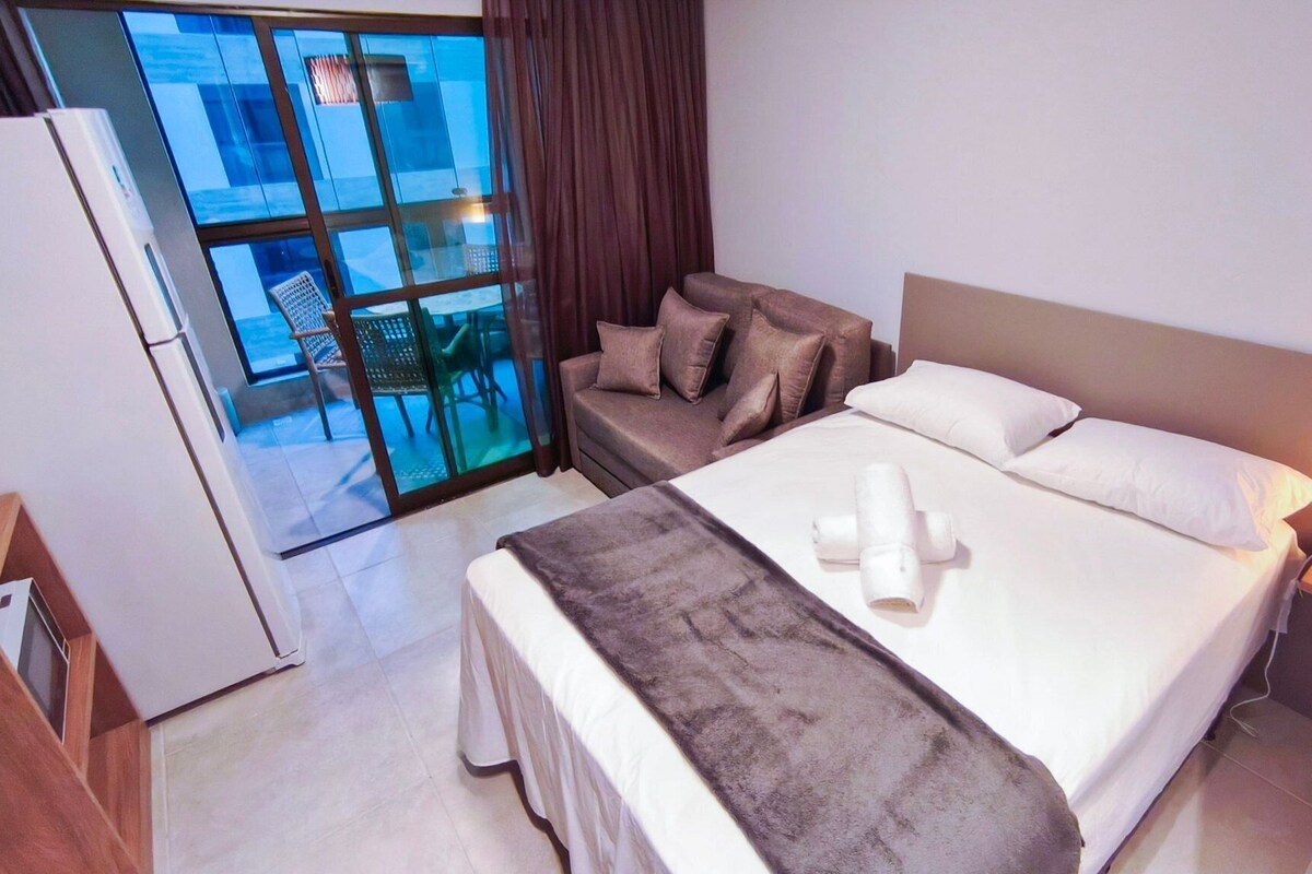 Ein Hotelzimmer mit Bett, Sofa, Schreibtisch und Blick ins Freie.