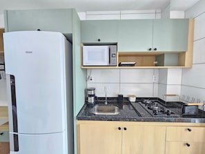 A kitchen with a white refrigerator, a microwave, a coffee maker, and wooden cabinets. - Max Carneiros Suites by CTA (Tamandaré)