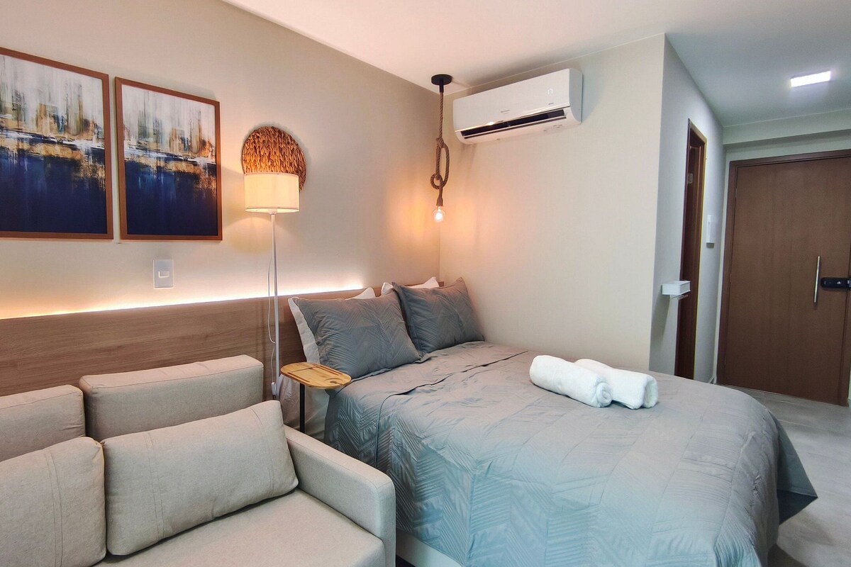 Ein Hotelzimmer mit einem Bett, einer Couch, einer Wand-Klimaanlage und einer Tür.