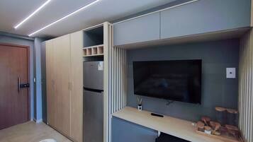 Une chambre moderne dotée d’armoires encastrées, d’un téléviseur à écran plat et d’une petite table sur laquelle sont posés des bocaux.