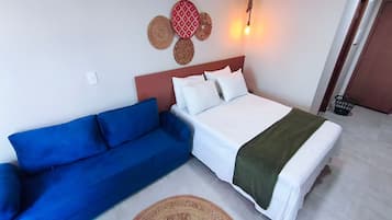 Um quarto com cama, um sofá azul e um objeto decorativo na parede.