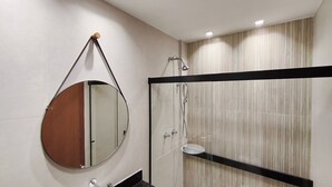 Un bagno moderno con uno specchio tondo, cabina doccia in vetro e lavabo con cornice nera.
