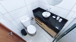 Une salle de bain avec des toilettes, un lavabo et un miroir.