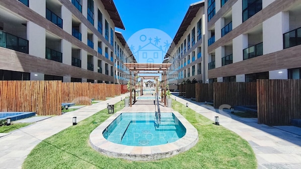 A modern building with a central pool, wooden fences, and a clear sky.
