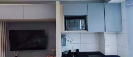 A compact kitchen with a flat-screen TV, a microwave, and a sink.