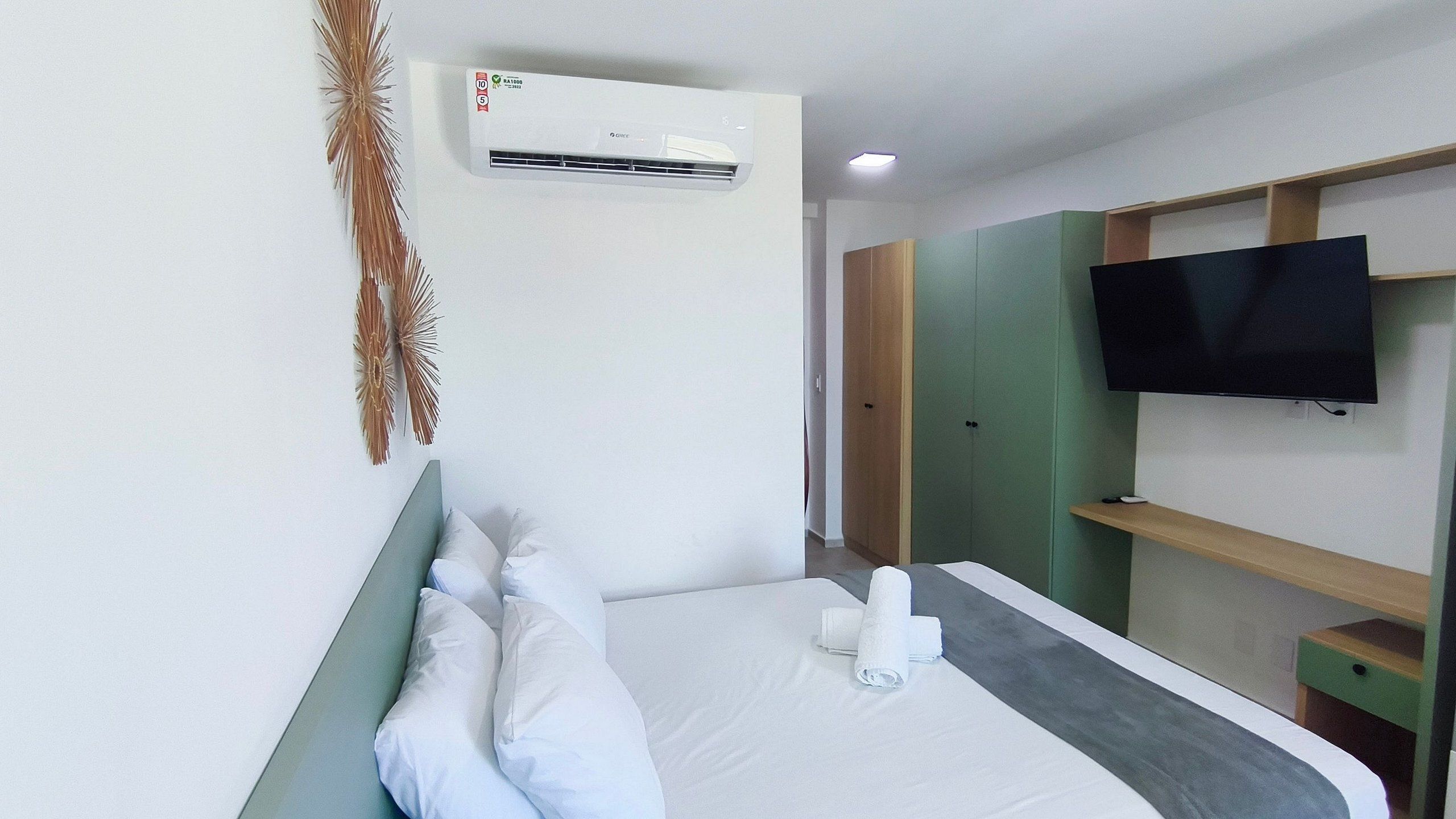 Habitació d'hotel amb llit, almoines, televisió de pantalla plana, aire condicionat i armari de fusta.